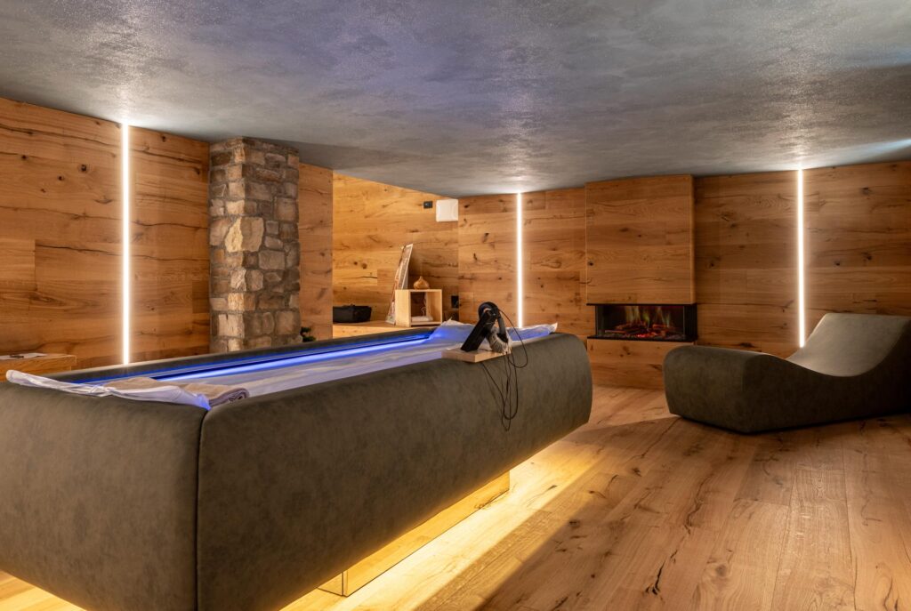Stanza wellness dell'Hotel Des Alpes a San Martino di Castrozza con sistema Zerobody Dry Float Starpool e parete con bosco.