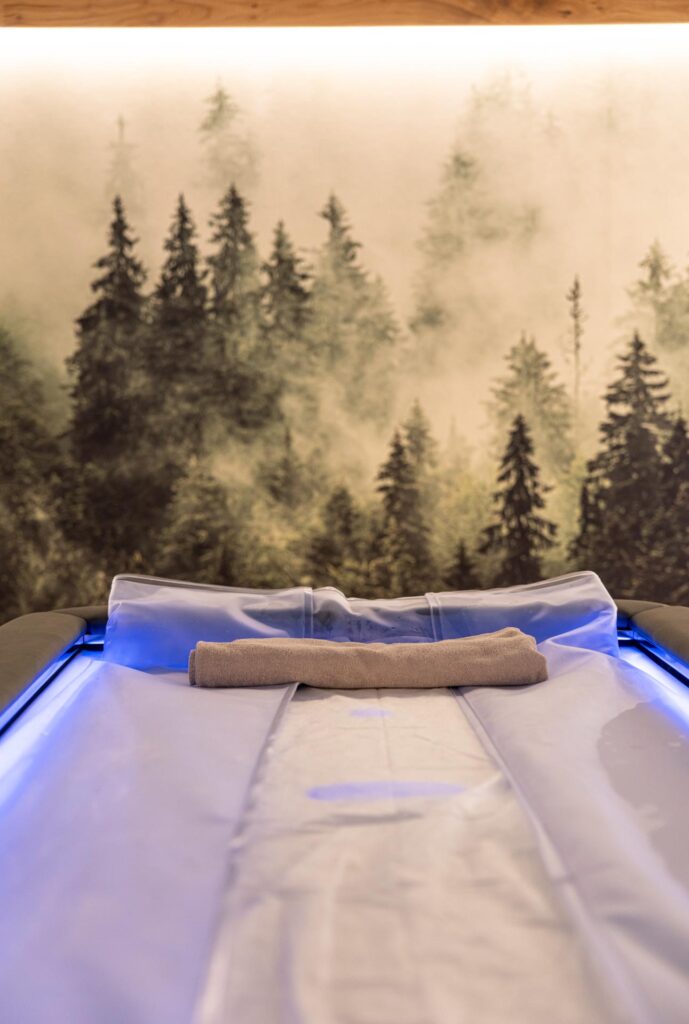 Stanza wellness dell'Hotel Des Alpes a San Martino di Castrozza con sistema Zerobody Dry Float Starpool e parete con bosco.